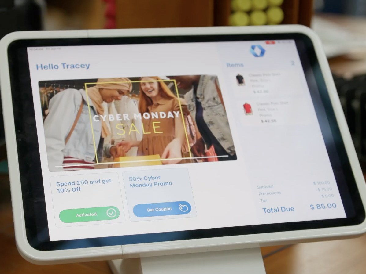 A Teamwork Commerce customer-facing display at checkout greeting the customer by name, with a targeted promotion, coupon offer, and live cart total