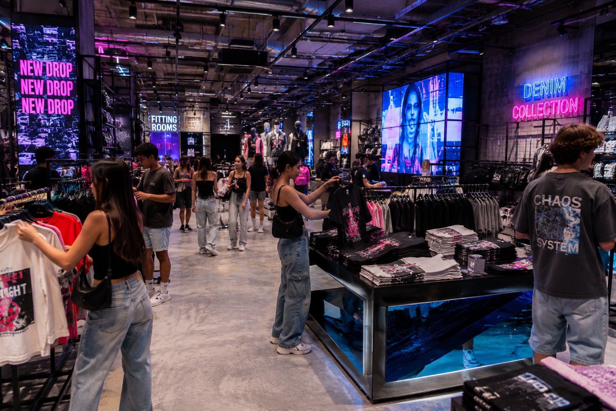 Shoppers browsing a fashion apparel floor with an associate at the counter